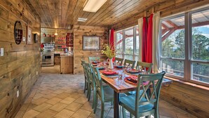 Een houten hut met een eethoek, keuken en grote ramen.