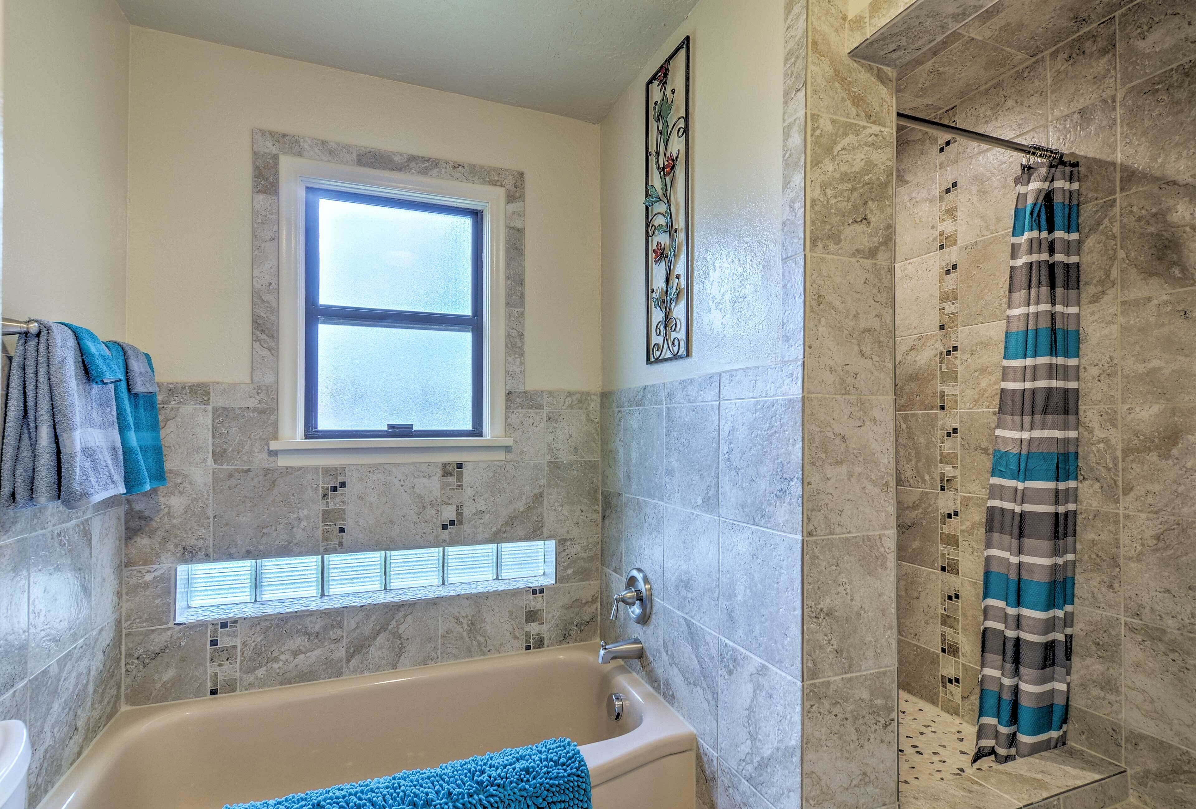 A bathroom with a bathtub, a shower, and a window.