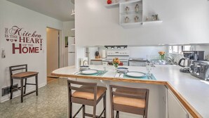 A modern kitchen with a central island, white cabinetry, and a decorative wall sign. - Panguitch Home w/ Patio ~ 24 Mi to Bryce Canyon (Panguitch)
