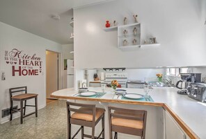 Una cocina moderna con una isla central, muebles blancos y un letrero decorativo en la pared.