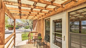 A covered patio with a wooden ceiling, a sliding glass door, and two chairs with a small table and potted plant. - Panguitch Home w/ Patio ~ 24 Mi to Bryce Canyon (Panguitch)