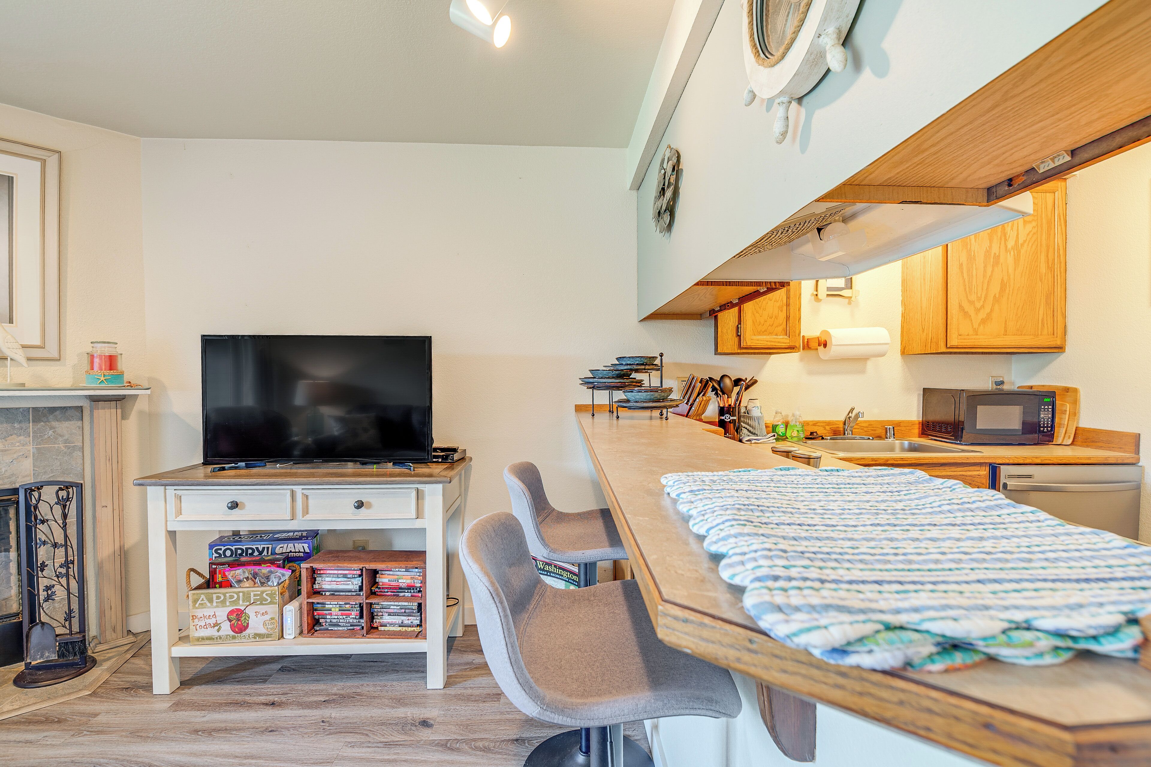 A compact living space with a television, a small kitchen area, and a dining table with a blanket.