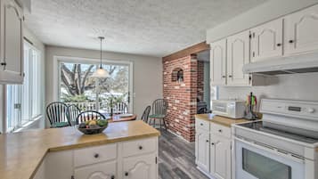 A kitchen with white cabinets, a brick fireplace, a microwave, and a large oven.