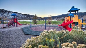 A playground with slides and climbing structures, set against a mountainous backdrop. - Magnificent Gypsum Retreat on the Colorado River! (Gypsum)