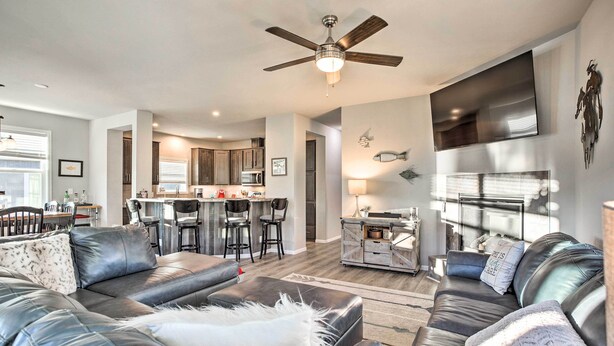 A modern living room with a leather sofa, a ceiling fan, and a kitchen area in the background. - Magnificent Gypsum Retreat on the Colorado River! (Gypsum)