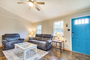 A living room with two grey sofas, a white coffee table, and a blue door.