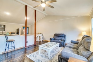 A modern living room with a grey sofa, a white coffee table, and a bar area with stools.