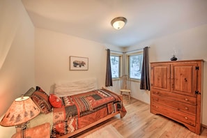 A bedroom with a bed, a wooden cabinet, a chair, and a window with curtains.