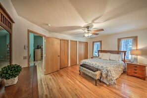 A bedroom with a wooden floor, a bed with a patterned bedspread, a ceiling fan, and a nightstand with a lamp. - Montana Home on 5 Acres: Near Lake Koocanusa! (Rexford)