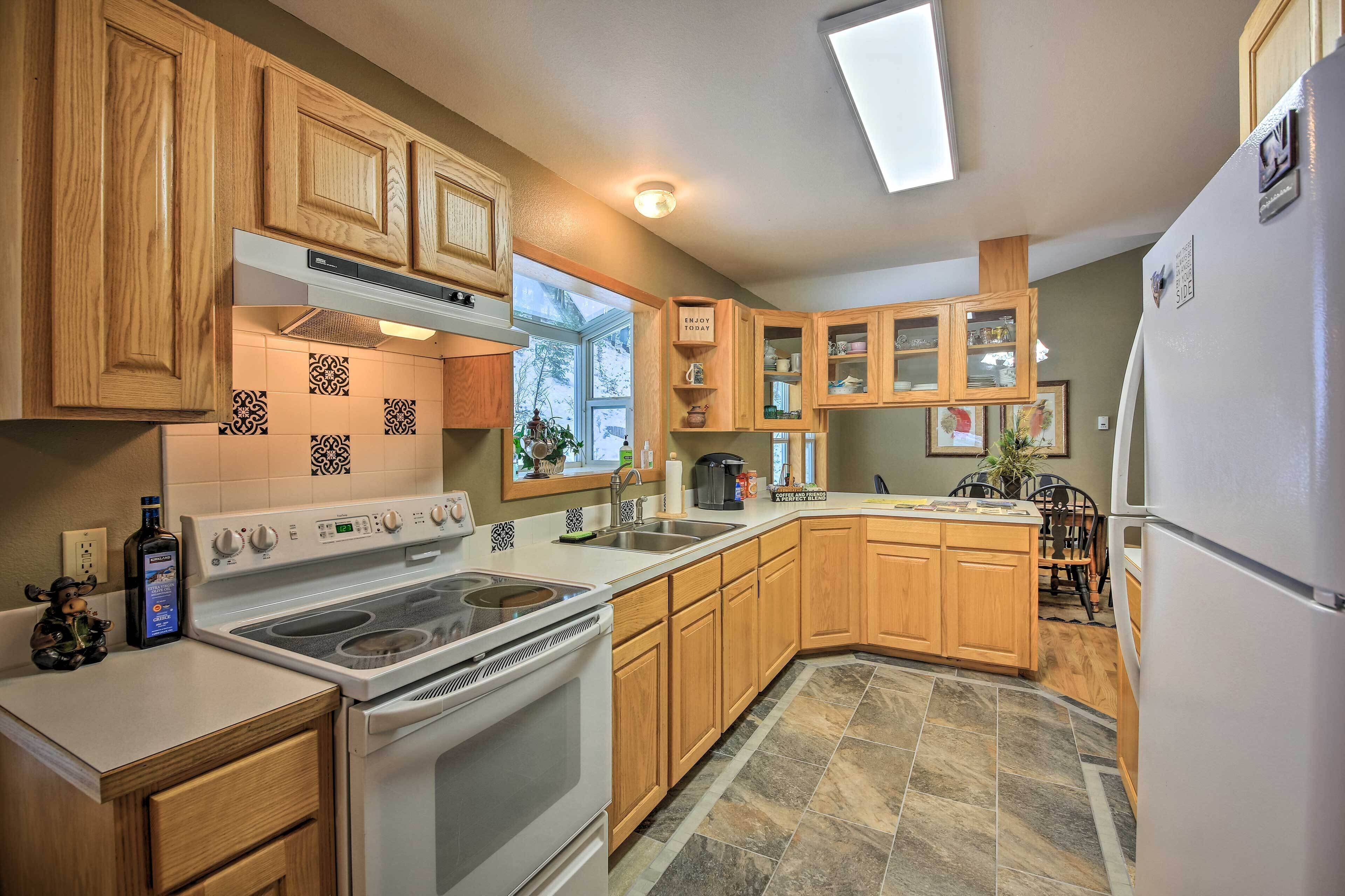 A kitchen with wooden cabinets, a stove, a refrigerator, and a window.
