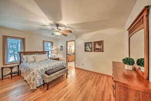 A bedroom with a wooden bed, a ceiling fan, and large windows. - Montana Home on 5 Acres: Near Lake Koocanusa! (Rexford)