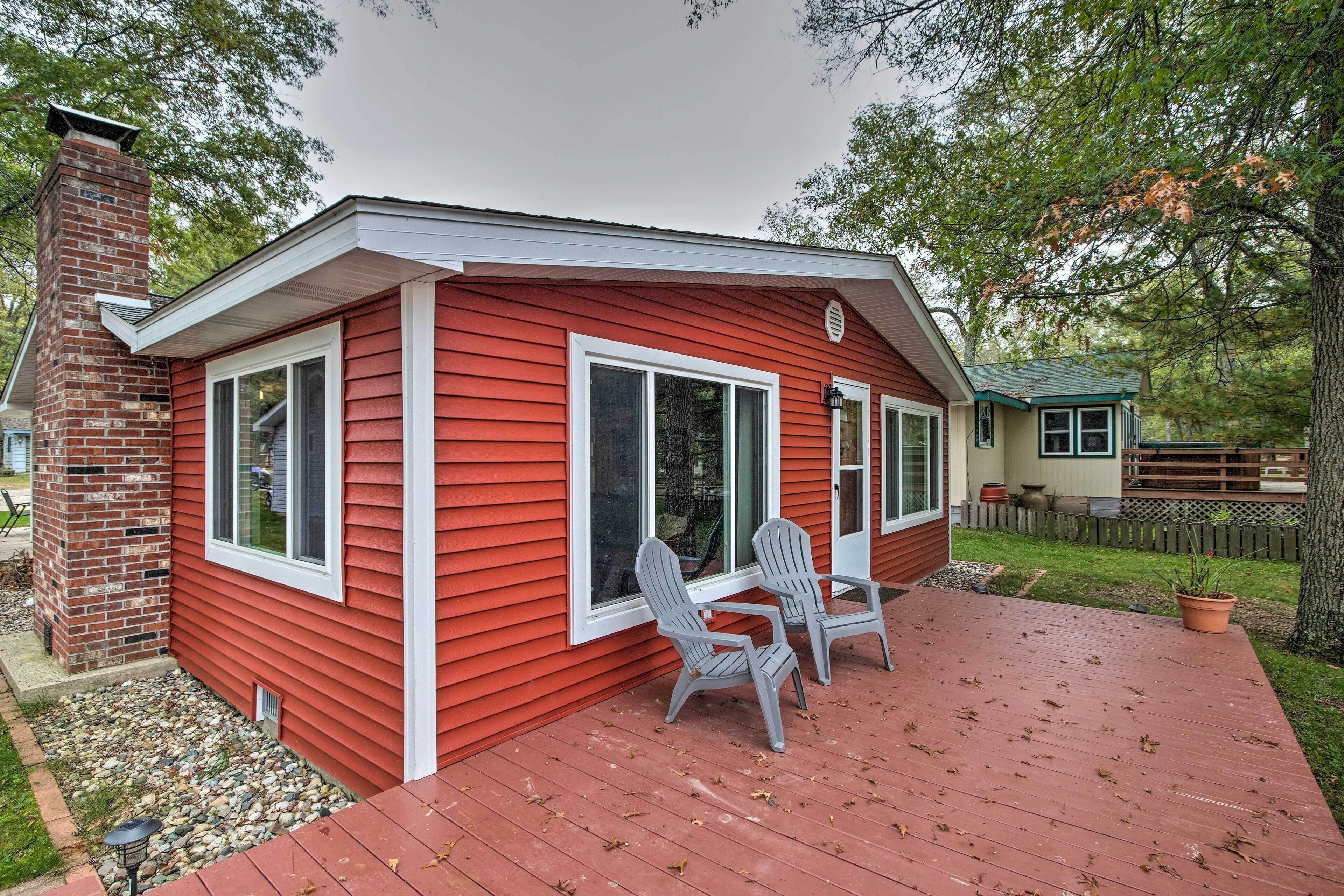 A red house with a chimney, a deck with Adirondack chairs, and a small porch.