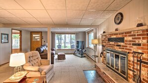 A cozy living room with a fireplace, a comfortable sofa, and a lamp. - National City Cottage w/ Patio, Steps to Lake! (National City)