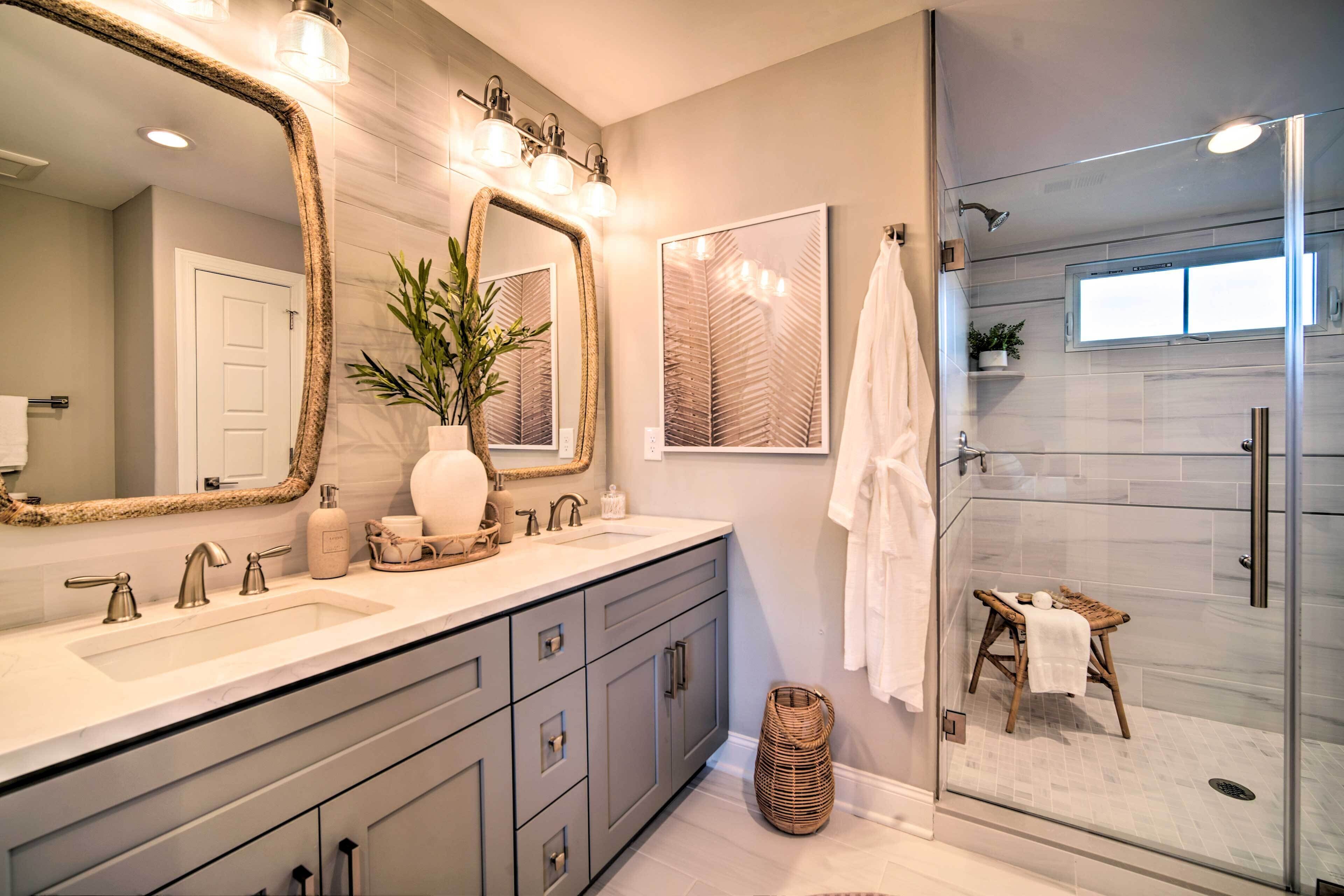 A modern bathroom with a large mirror, two sinks, and a glass-enclosed shower.
