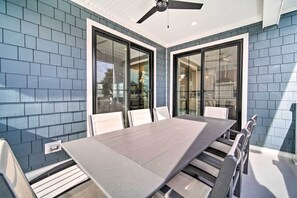 Ein Essbereich mit langem Tisch und Stühlen, großen Fenstern und einem Deckenventilator.