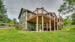 Une grande maison à deux étages, dotée d’une terrasse en bois et d’un porche couvert.