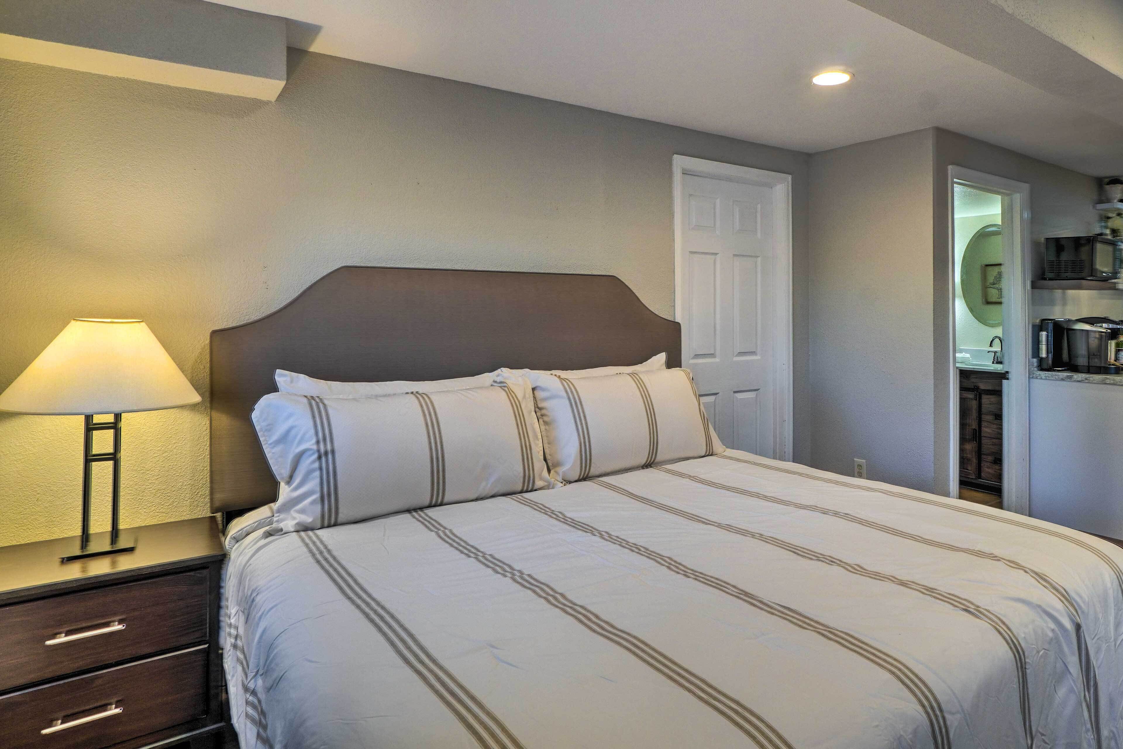 A neatly made bed with a striped bedspread, a bedside lamp, and a dark wooden nightstand with drawers.