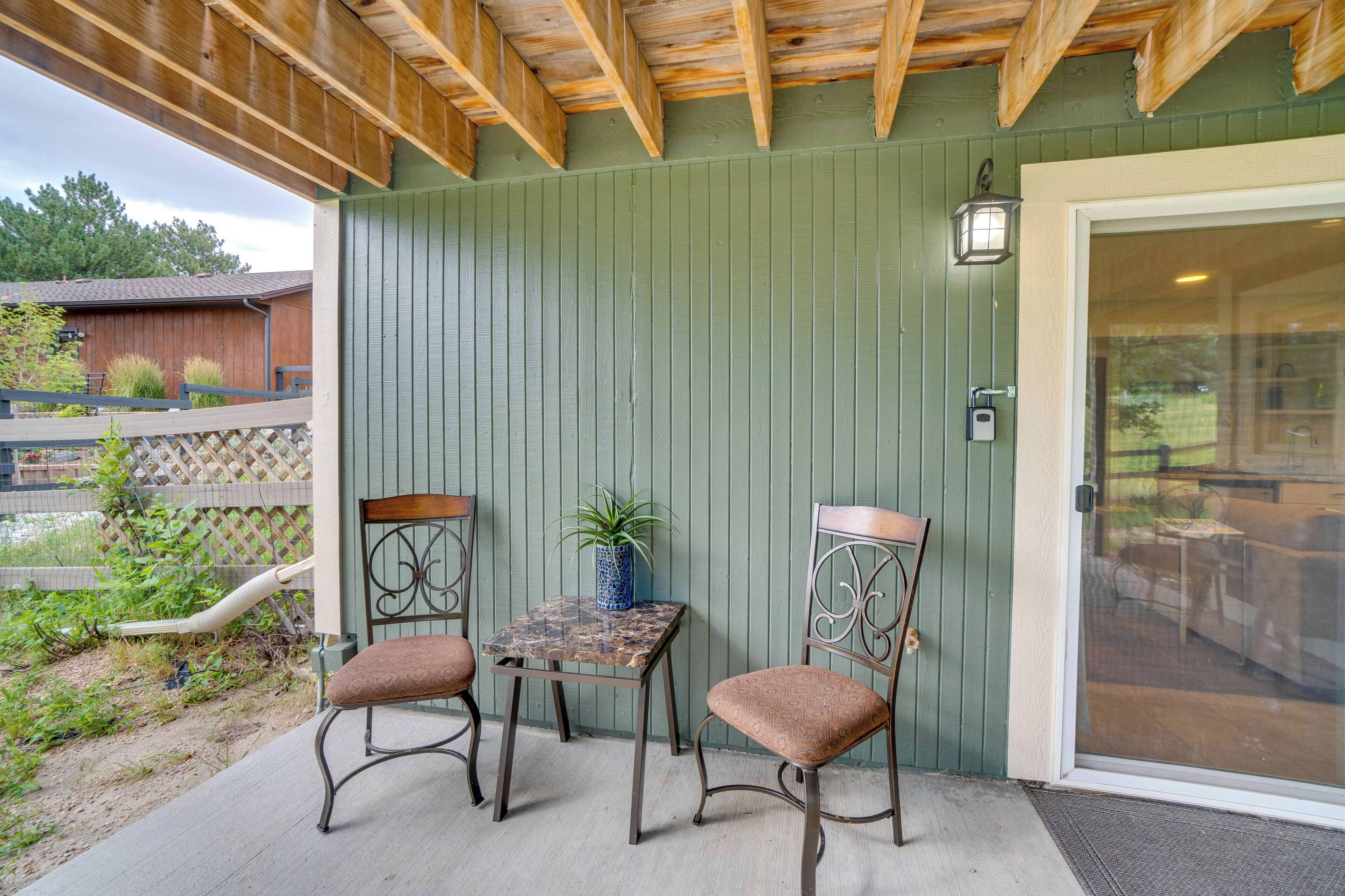An outdoor patio with a wooden ceiling, a green wall, and a glass door leading to an interior space.