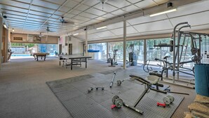 Una palestra con attrezzature per esercizi, un tavolo da ping pong e ampie finestre.
