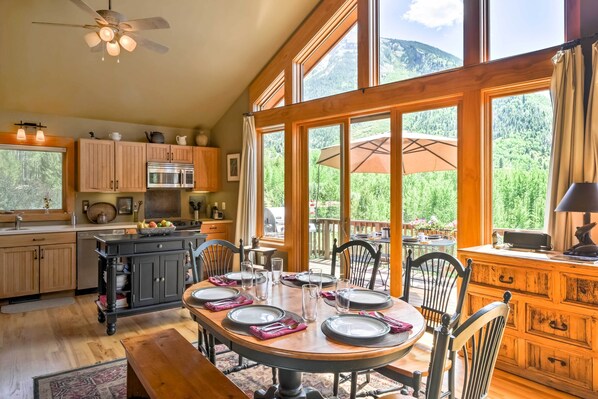 A spacious kitchen with wooden cabinets, a dining table set for six, and large windows offering a mountain view. - Peaceful Marble, Colorado Home w/ Deck & Mtn Views (Carbondale)