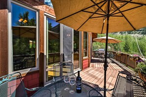 A deck with outdoor seating, a table with a bottle and glasses, and a large umbrella. - Peaceful Marble, Colorado Home w/ Deck & Mtn Views (Carbondale)