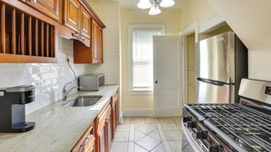 A kitchen with wooden cabinets, a stainless steel refrigerator, a gas stove, and a Keurig coffee maker. - Quaint Omaha Home < 5 Mi to Downtown! (Omaha)