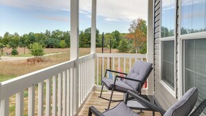 A covered porch with two chairs and a table, overlooking a grassy area with trees and a clear sky. - Family Home in Rapid City ~ 4 Mi to Torch Lake! (Rapid City)