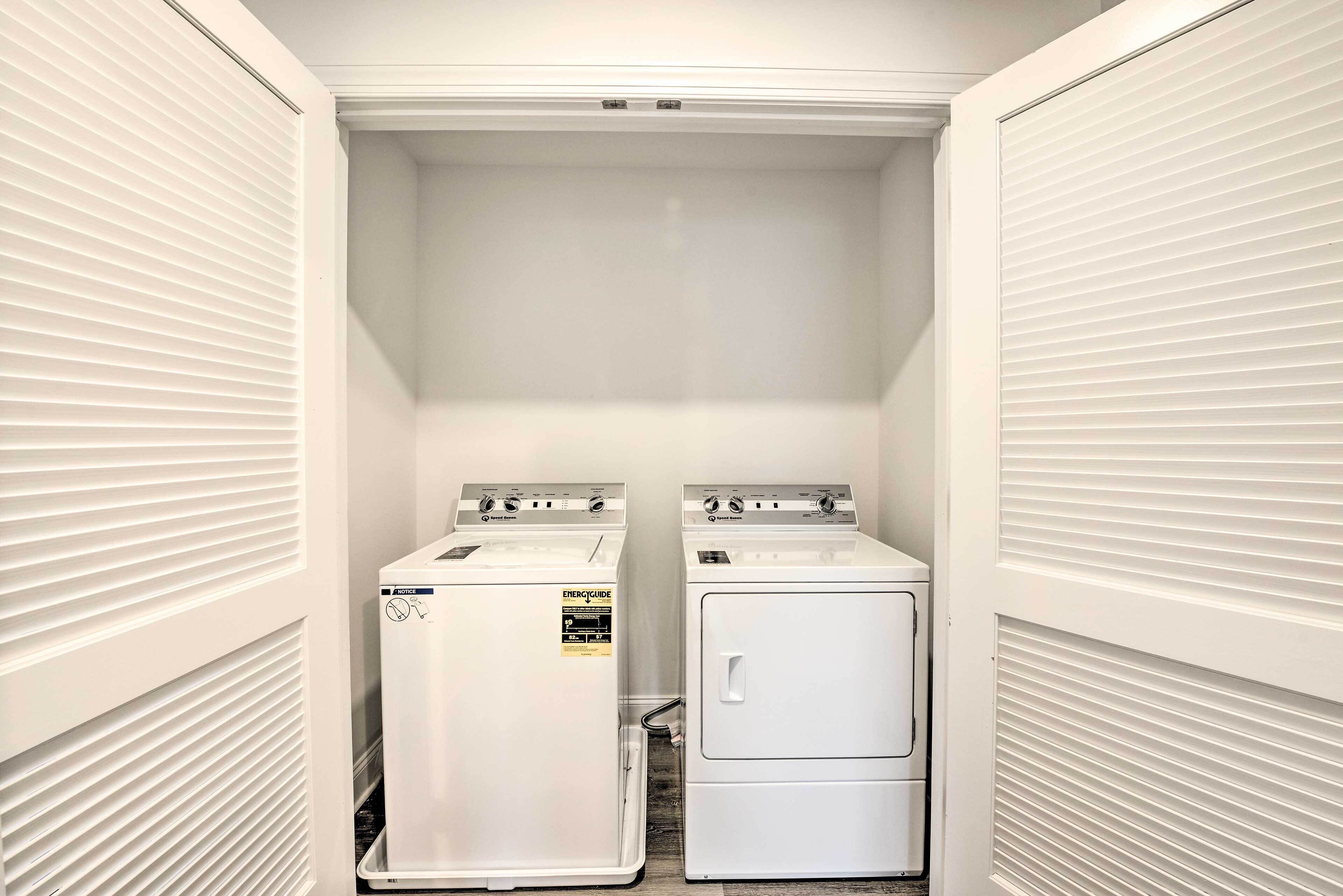 A laundry room with two front-loading washers and dryers, white walls, and a vented ceiling.