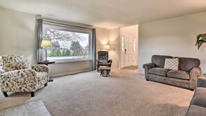 A living room with a large window, a sofa, a chair, and a lamp. - Portland Area Home, 32 Mi to Mt Hood! (Boring)