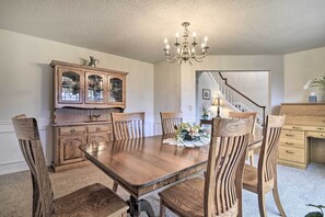 A dining room with a wooden table and chairs, a chandelier, and a wooden cabinet. - Portland Area Home, 32 Mi to Mt Hood! (Boring)