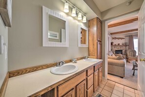 A bathroom with two sinks, wooden cabinets, and a large mirror.