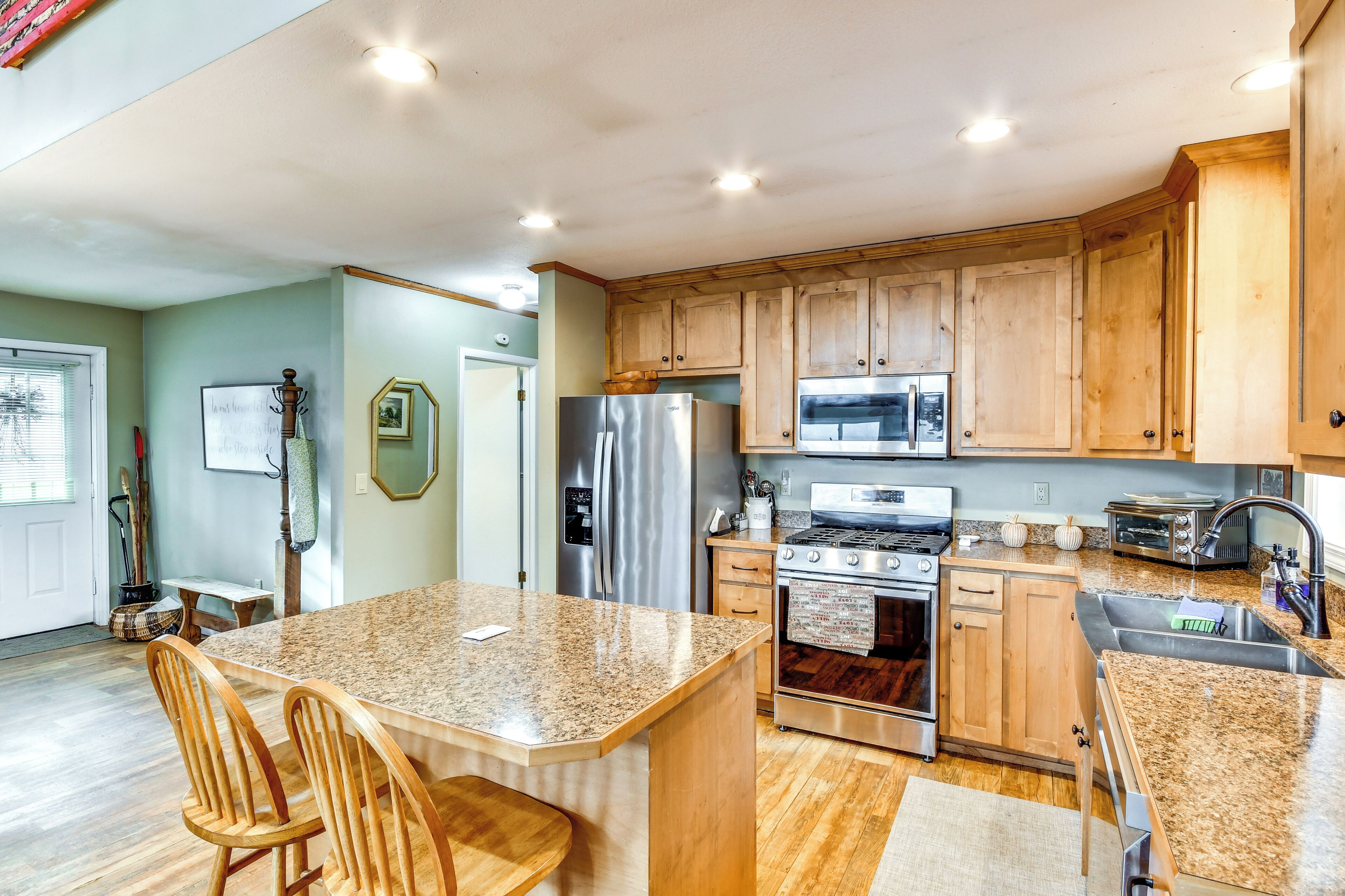 A spacious kitchen with wooden cabinets, stainless steel appliances, and a granite countertop.