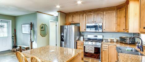 A spacious kitchen with wooden cabinets, stainless steel appliances, and a granite countertop.