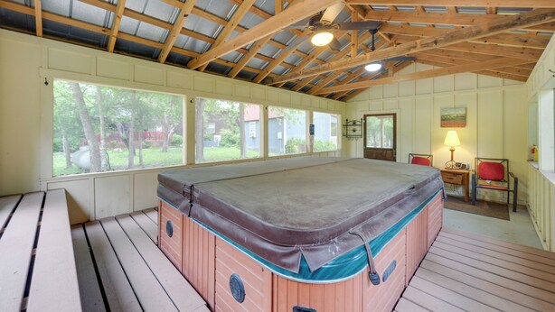 Un jacuzzi en una habitación con vigas de madera, ventanas amplias y vistas al exterior.