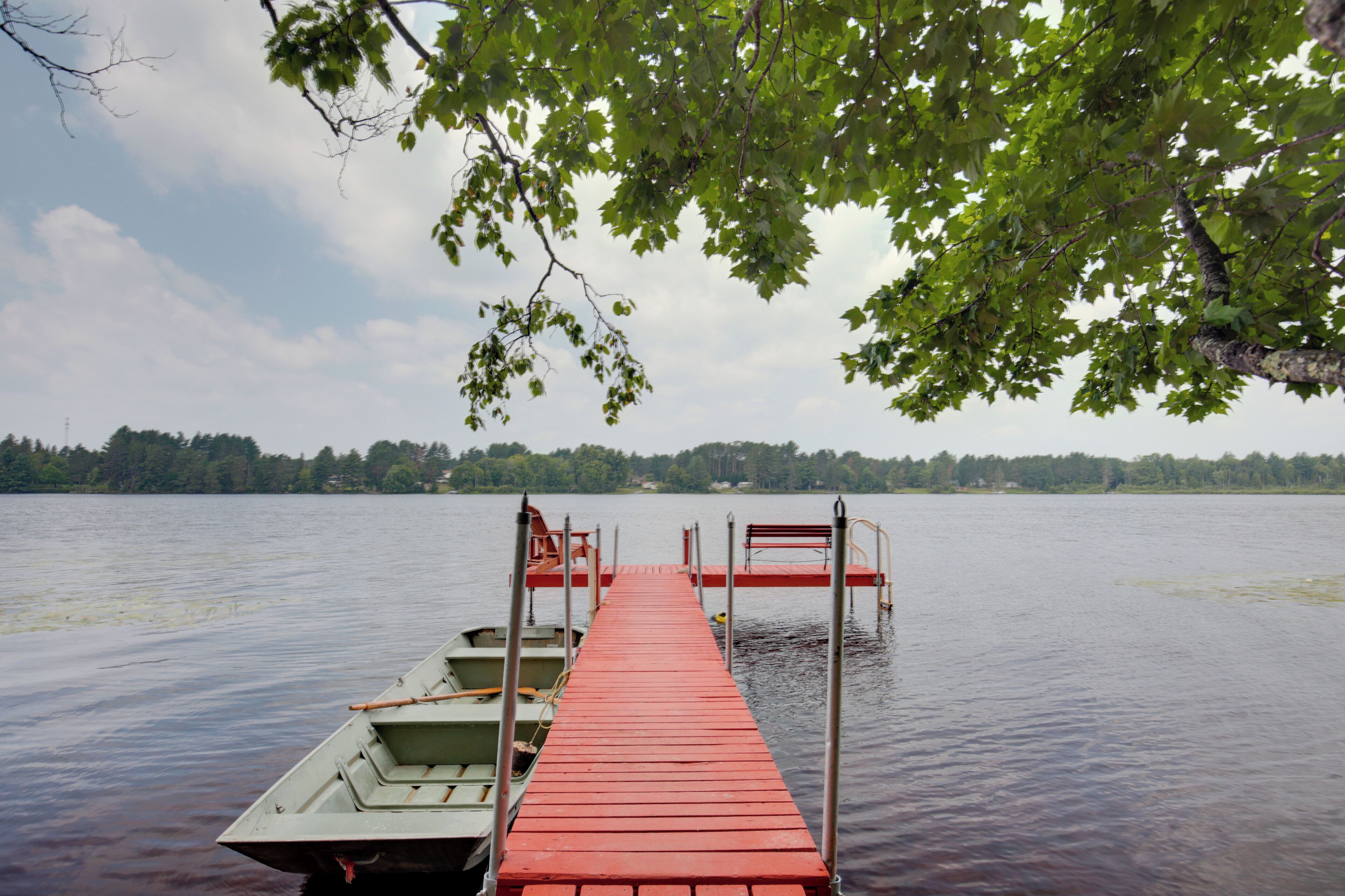 A wooden dock extending into a calm lake, with boats docked on the left and a forested shoreline in the background.