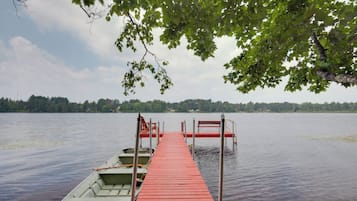 A wooden dock extending into a calm lake, with boats docked on the left and a forested shoreline in the background.