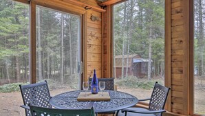 A wooden cabin with a round table and chairs, a bottle of wine, and a tray. - Rhinelander Home - Jennie Webber Lake On-site (Rhinelander)