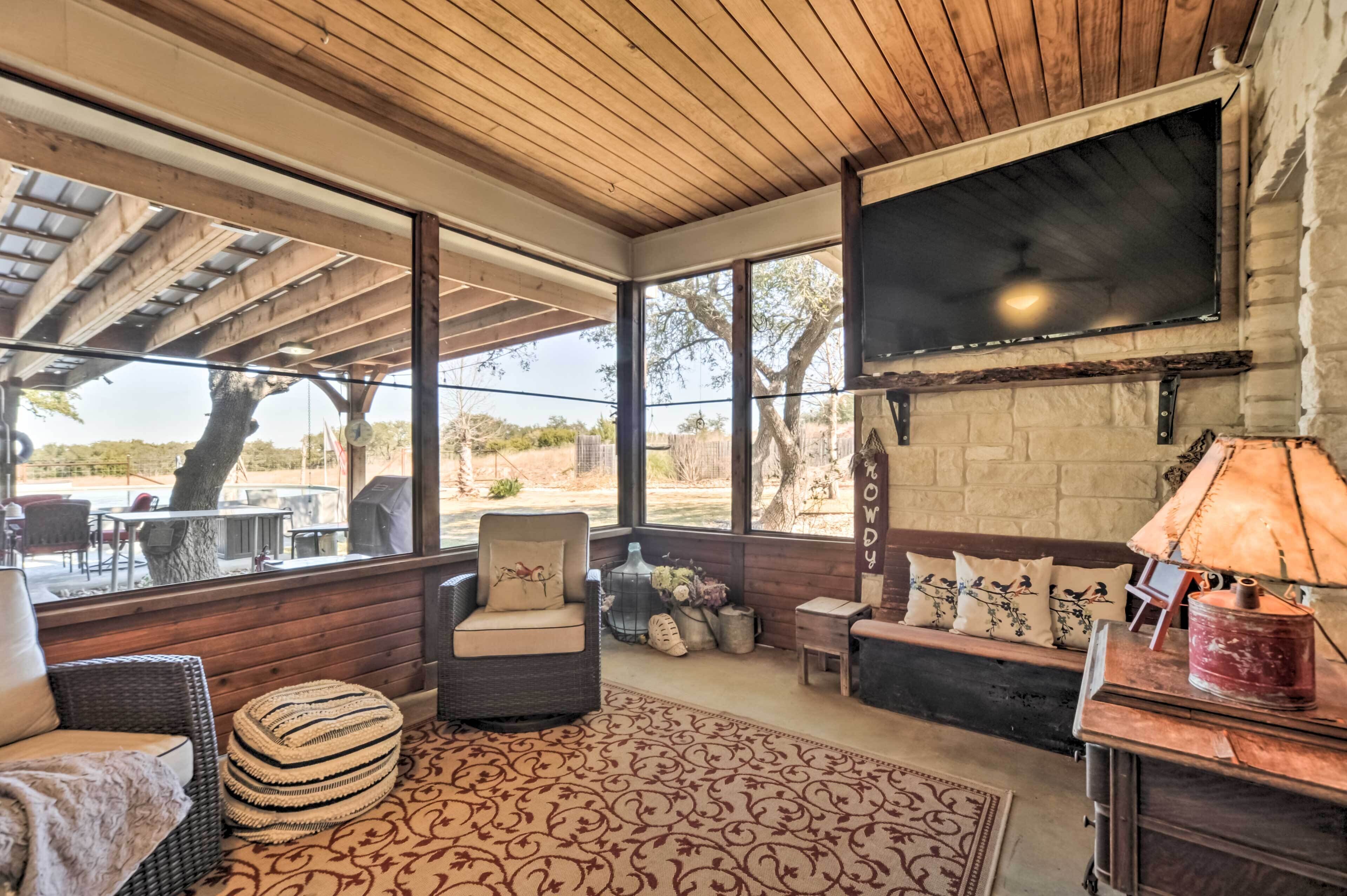 A cozy living room with a fireplace, comfortable seating, and large windows overlooking a scenic outdoor area.