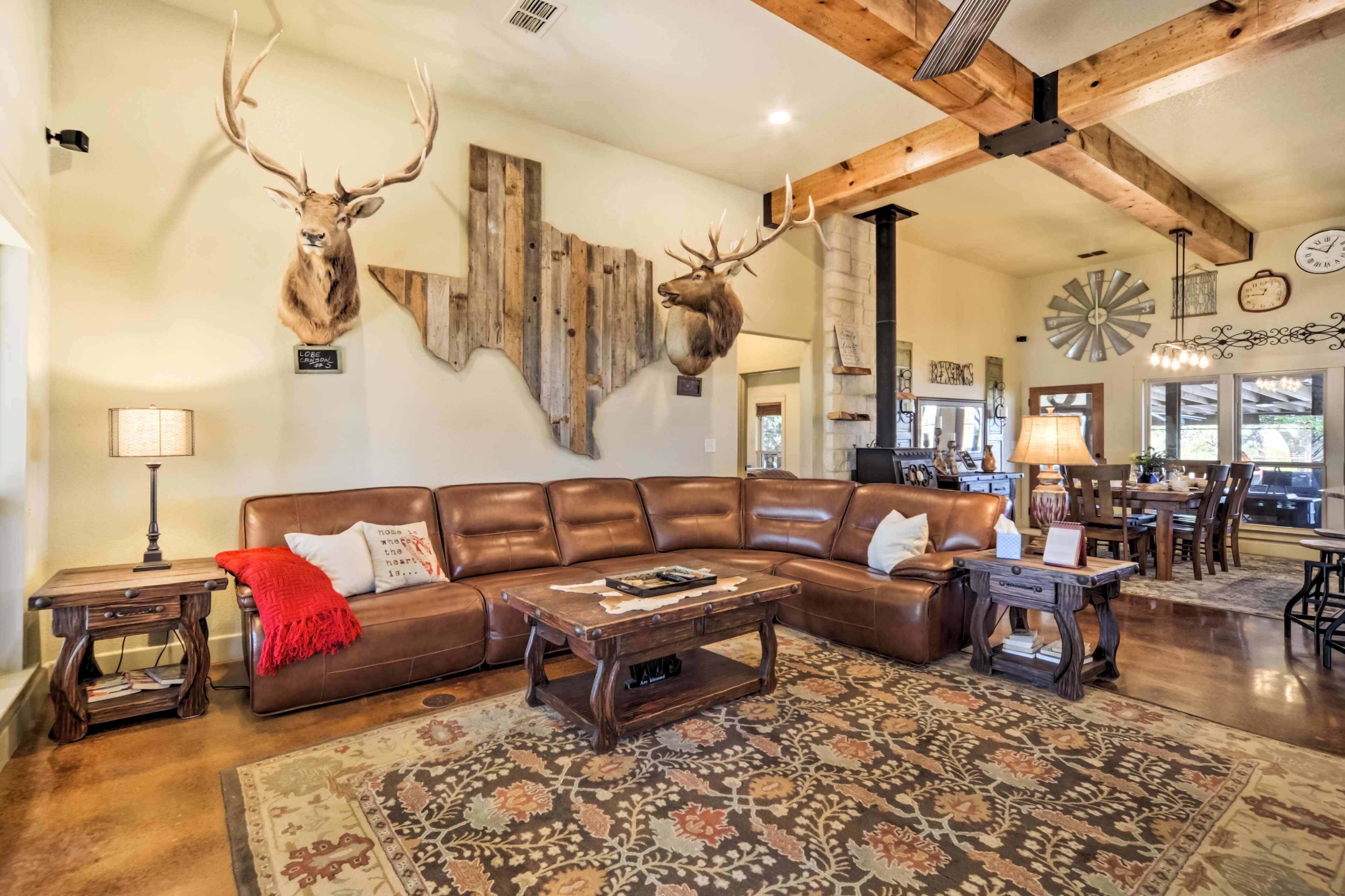 Ein geräumiges Wohnzimmer mit einem braunen Ledersofa, einem Couchtisch aus Holz und einem gemusterten Teppich.