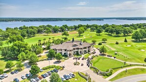 Ein großes, zweistöckiges Gebäude mit einem zentralen Innenhof, umgeben von einem Golfplatz und einem Gewässer.