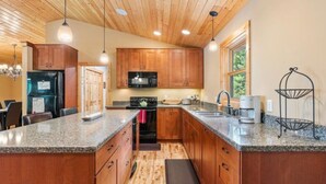 A kitchen with wooden cabinets, granite countertops, a microwave, stove, and a coffee maker.