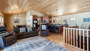 A spacious living area with a wooden ceiling, a kitchen, a dining area, and a bar.