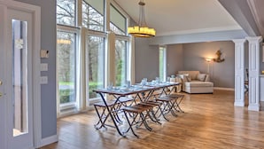 A dining area with a long table set for multiple people, large windows, and a chandelier. - Monticello Home w/ Multi-level Deck on 2 Acres! (Monticello)