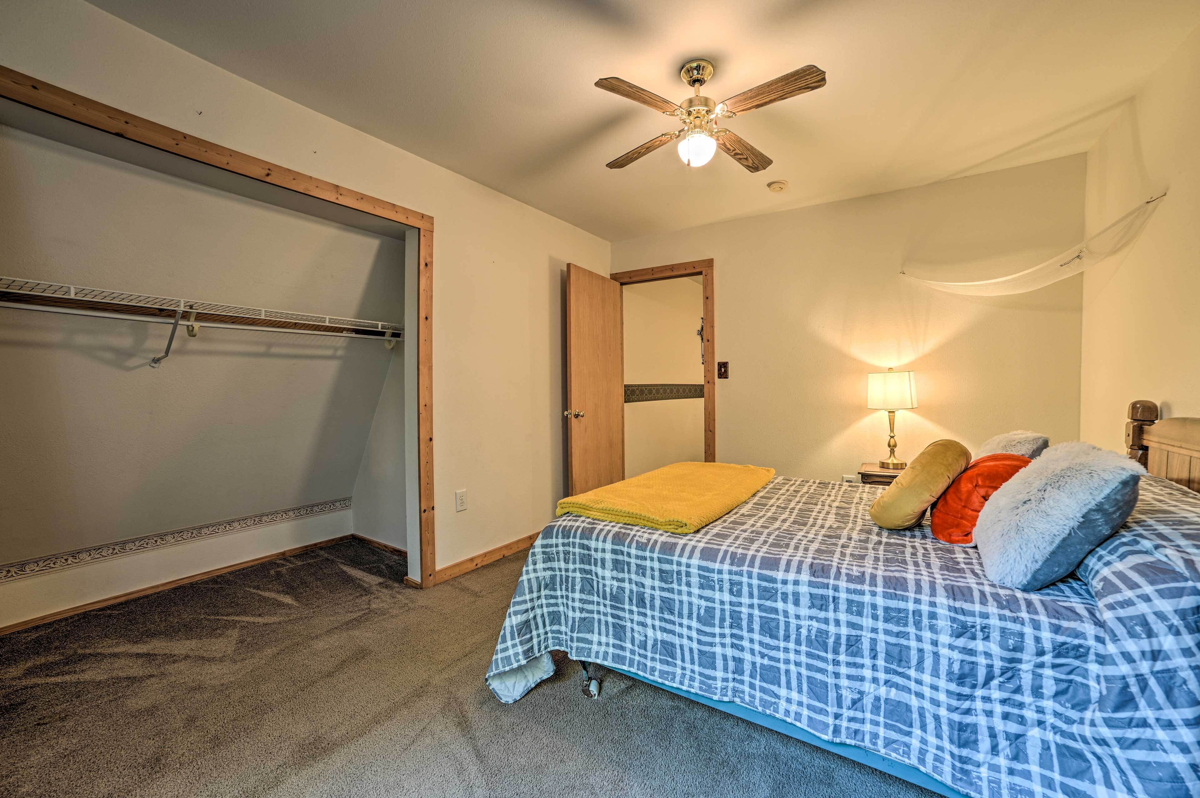 A bedroom with a bed, a ceiling fan, a nightstand with a lamp, and a wardrobe.