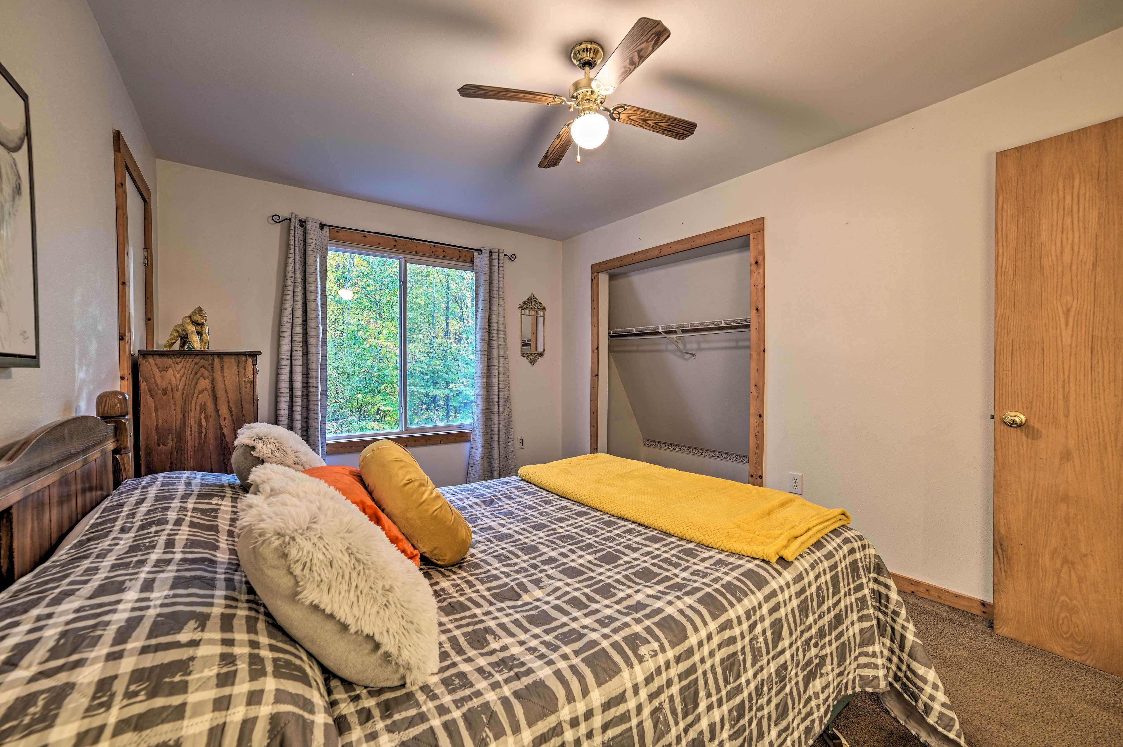 Une chambre à coucher avec un lit, un ventilateur de plafond, une fenêtre avec des rideaux et une porte.