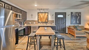 A modern kitchen with stainless steel appliances, a wooden dining table, and a cozy seating area with a sofa and cushions. - 4 Mi to Dtwn: Rustic Fort Worth Apt (Fort Worth)