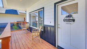 A wooden deck with two wicker chairs and a bench, a white door with a 'Welcome to our Home' sign, and a window with a view of the neighborhood. - 3 Mi to Lake Pend Oreille: Home w/ Deck & Yard (Ponderay)
