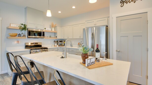 A modern kitchen with white cabinetry, stainless steel appliances, and a central island with bar stools. - 3 Mi to Lake Pend Oreille: Home w/ Deck & Yard (Ponderay)