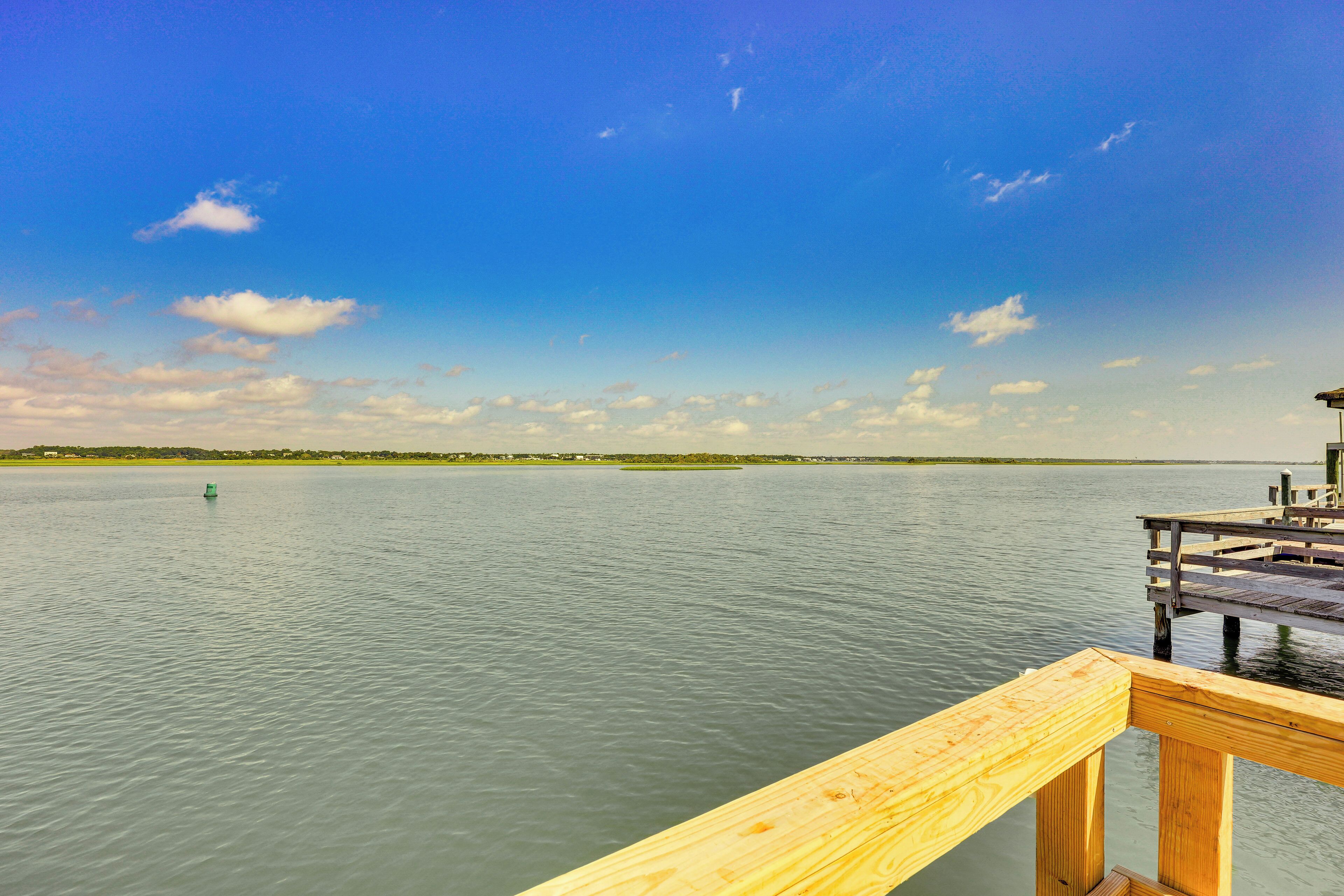 A wooden dock extending into calm water with a clear sky.