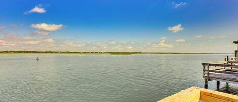 A wooden dock extending into calm water with a clear sky.